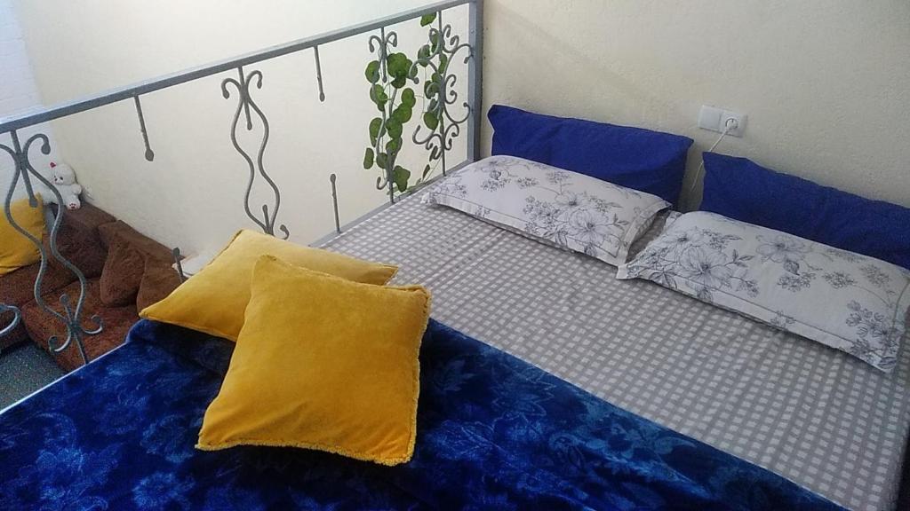 Una cama con sábanas azules y almohadas amarillas. en Двухуровневая квартира студия - Duplex studio apartment, en Dushanbe