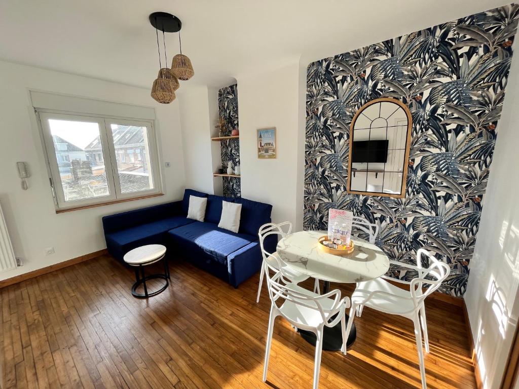 een woonkamer met een blauwe bank en een tafel bij Les appartements d'Ostende in Calais