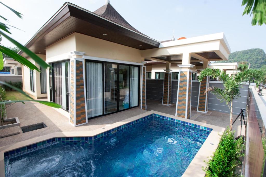 a villa with a swimming pool in front of a house at Aonang Oscar Pool Villas in Ao Nang Beach