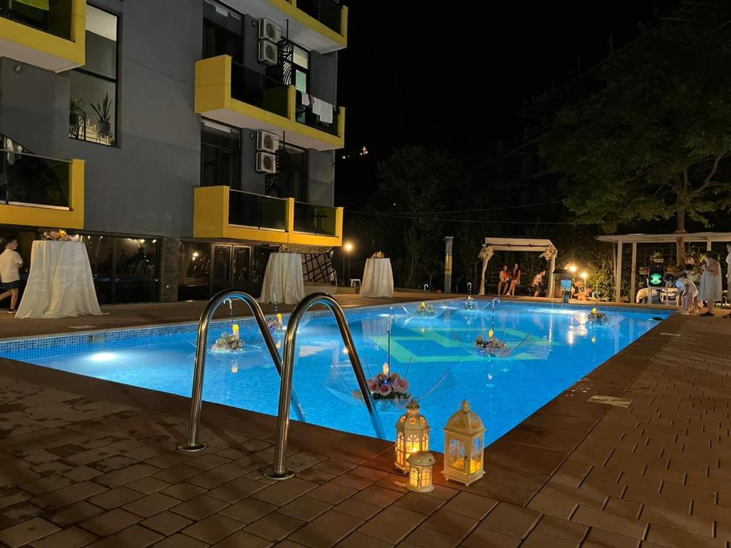 een groot zwembad 's nachts met drankjes erin bij Casa Del Mar in Kvariati