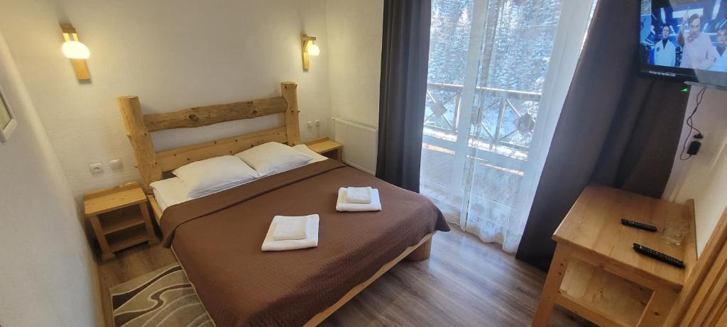 een slaapkamer met een bed met twee handdoeken erop bij Готель RIVER HILL in Mykulychyn