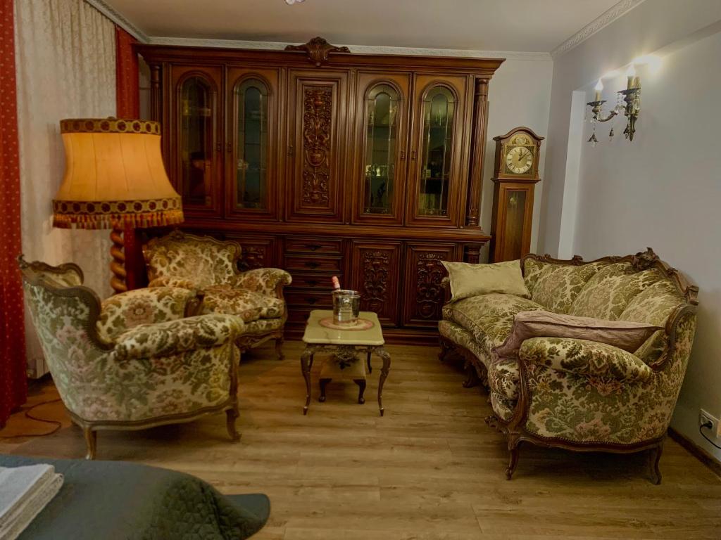 Una sala de estar con un sofá y sillas y un reloj. en Apartament Ultraconfort, en Iaşi