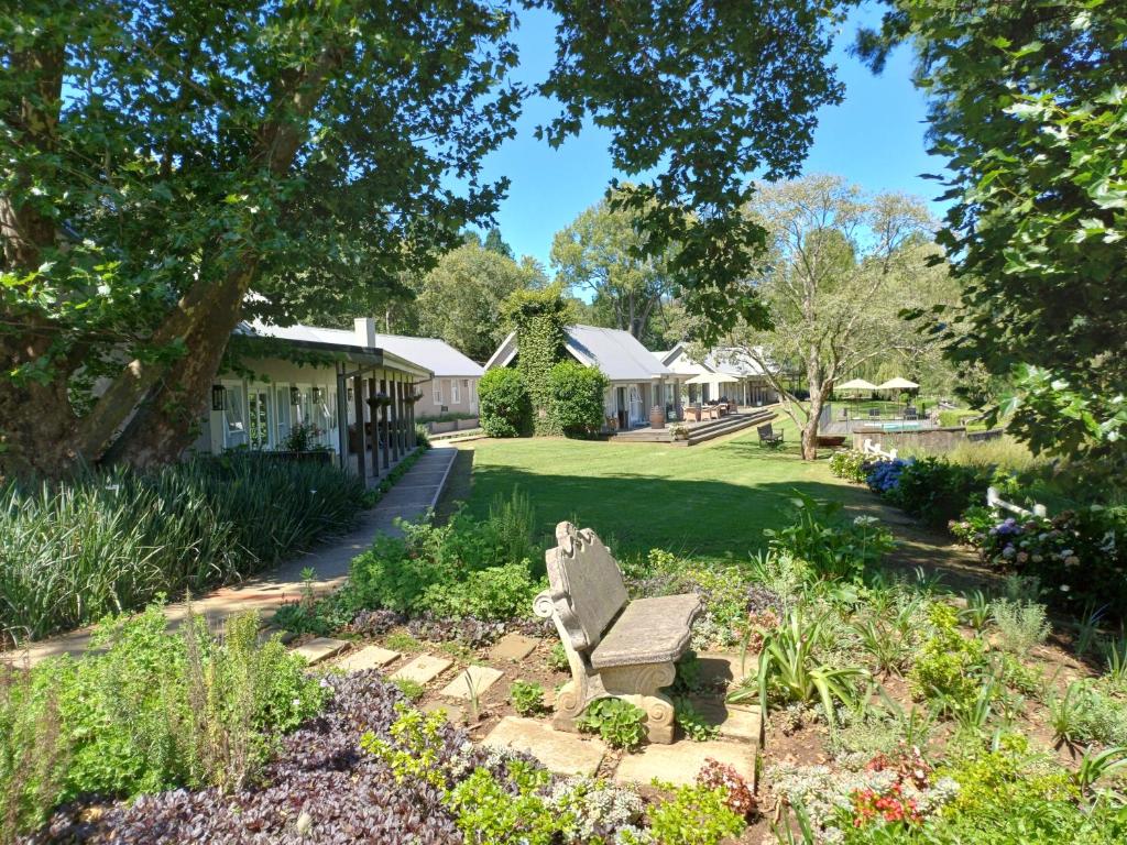 un jardin avec un banc devant un bâtiment dans l'établissement Bosch Hoek Golf & Lodge, à Balgowan