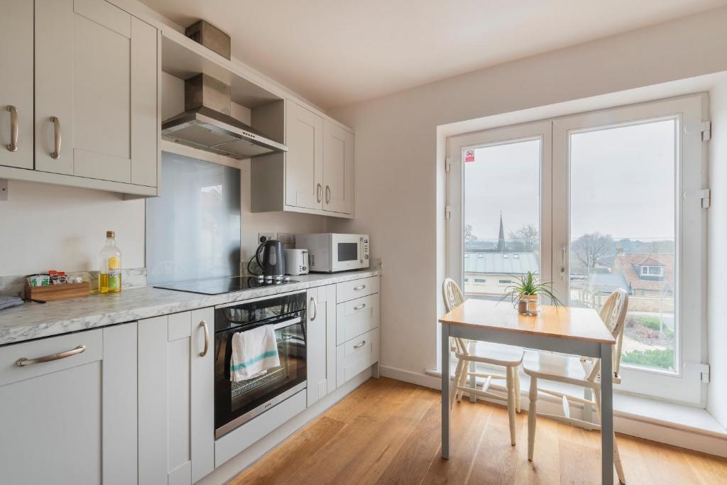 a kitchen with white cabinets and a table and a window at Stylish 3 bedroom house with garage in Frome