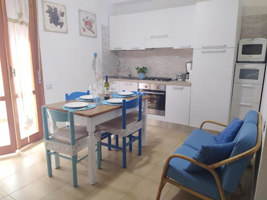 una cucina con tavolo in legno e sedie blu di Casa Marina a Carloforte