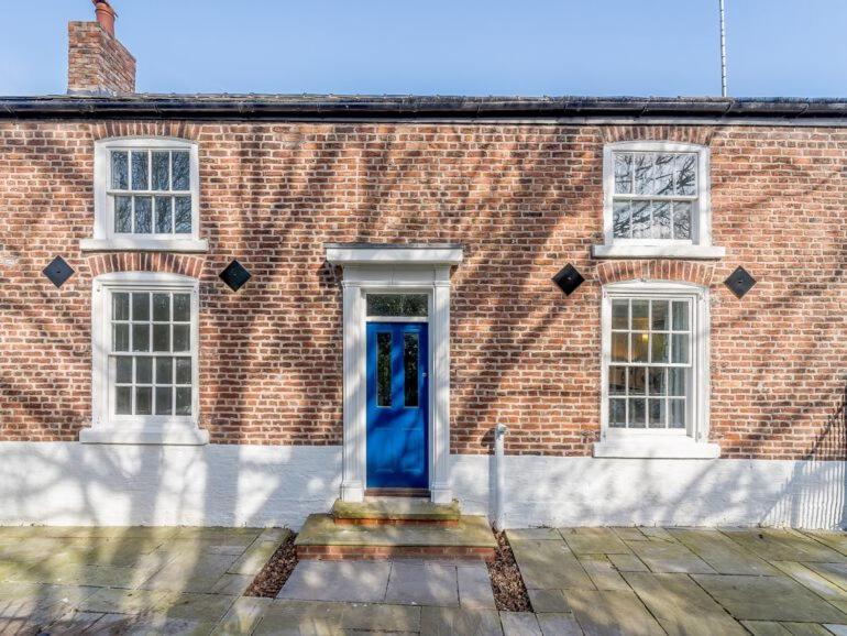 a brick building with a blue door and two windows at Classy yet cosy and close to Chester City Centre in Chester
