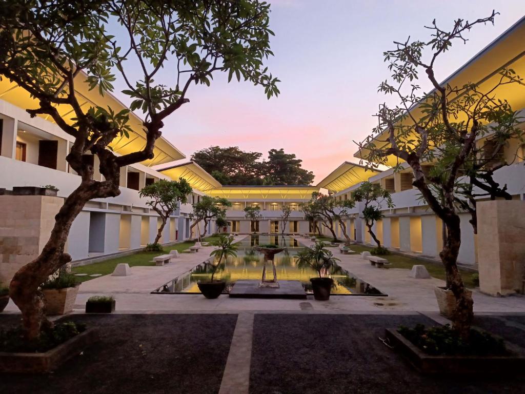 a courtyard of a building with trees and a fountain at Kuta Living in Kuta