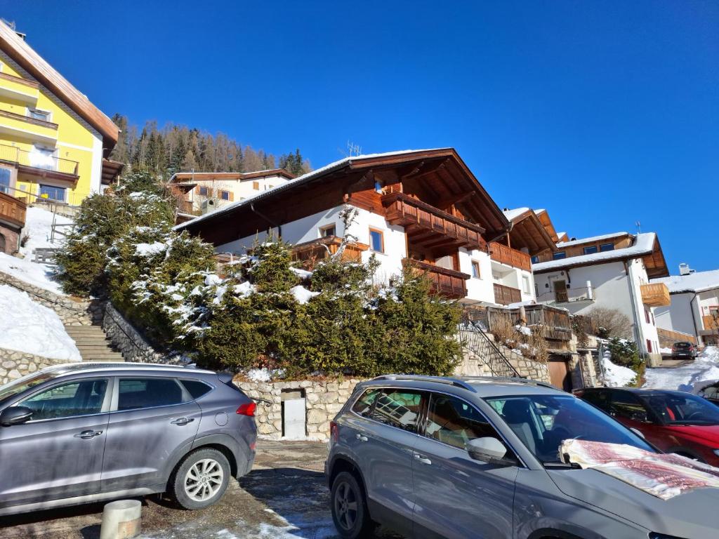 twee auto's geparkeerd op een parkeerplaats voor een gebouw bij Apartments Insam in Santa Cristina in Val Gardena