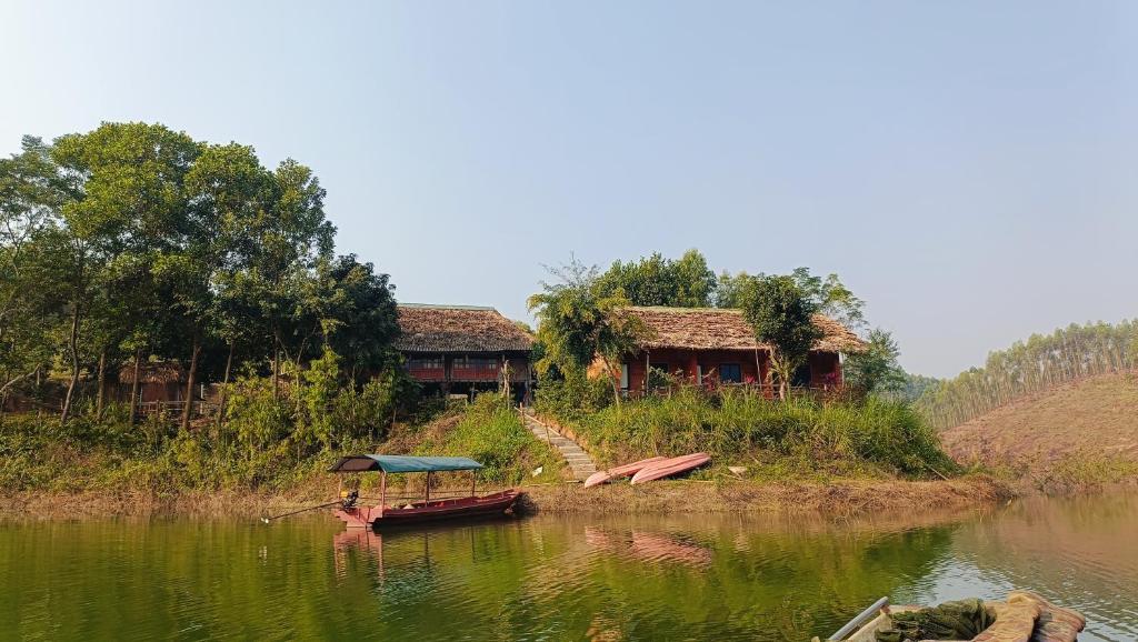a small house on the edge of a body of water at Giang Tien Homestay-VuLinh Farmstay ThacBa in Yên Bình