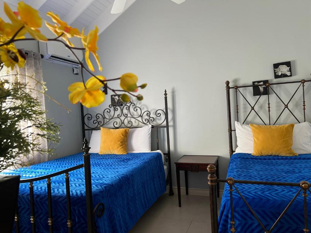 a bedroom with two beds with blue sheets and yellow pillows at Isle Be Back Villa in Priory