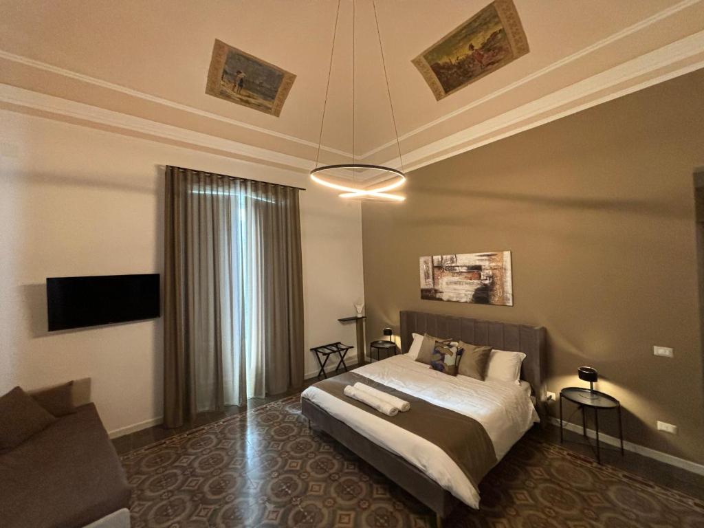 ein Schlafzimmer mit einem Bett, einem TV und einem Sofa in der Unterkunft Celeste Rooms in Catania
