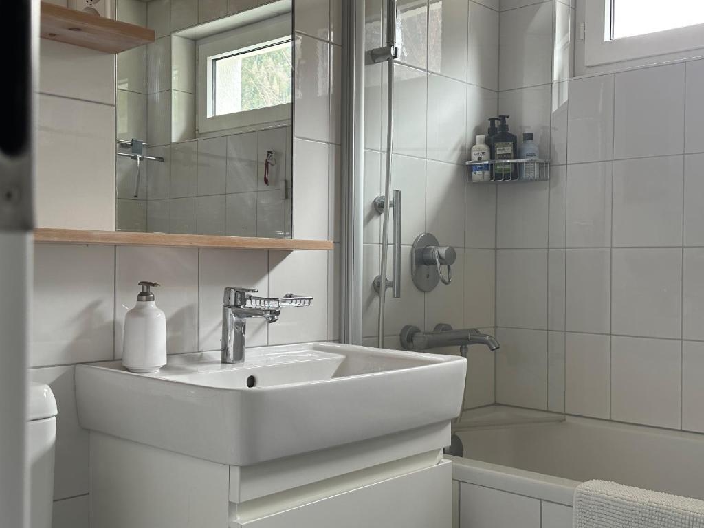 a white bathroom with a sink and a shower at Chasa Stefania mit rundum Bergblick und Garten in Scuol
