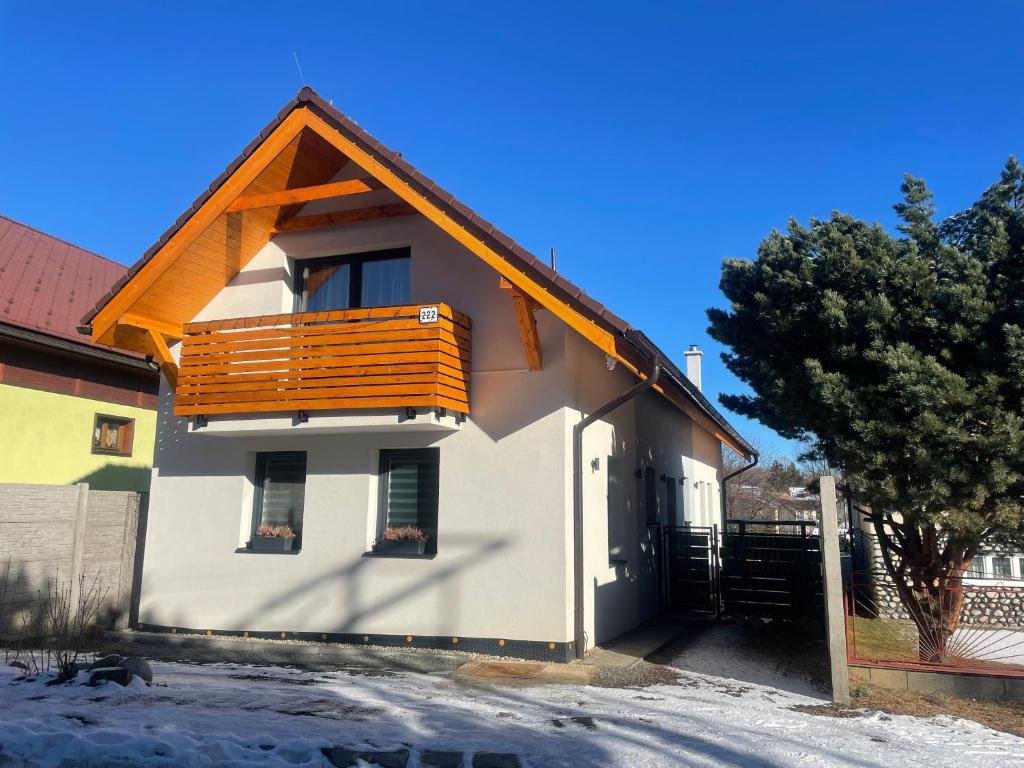 a white house with a wooden balcony on it at Vila Mima in Nová Lesná