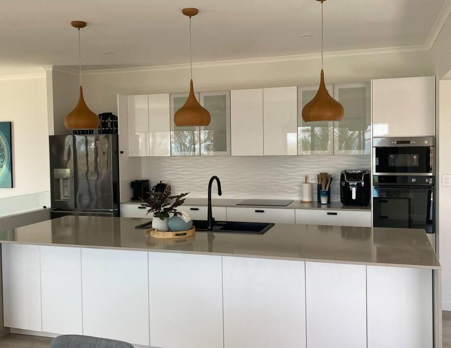 a kitchen with white cabinets and stainless steel appliances at ARay at Cooee Bay - Apt B - Beach House Yeppoon in Yeppoon