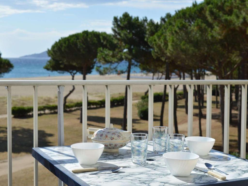une table avec des bols et des verres sur un balcon dans l'établissement Appartement 2 pièces, 5 couchages, front de mer - Argeles-sur-Mer, Parking, Animaux admis - FR-1-225-332, à Argelès-sur-Mer