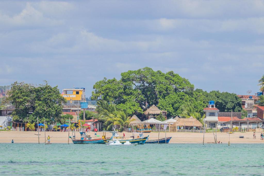 einen Strand mit Booten im Wasser neben einem Strand in der Unterkunft Pousada e Restaurante Stella Maris in São José da Coroa Grande