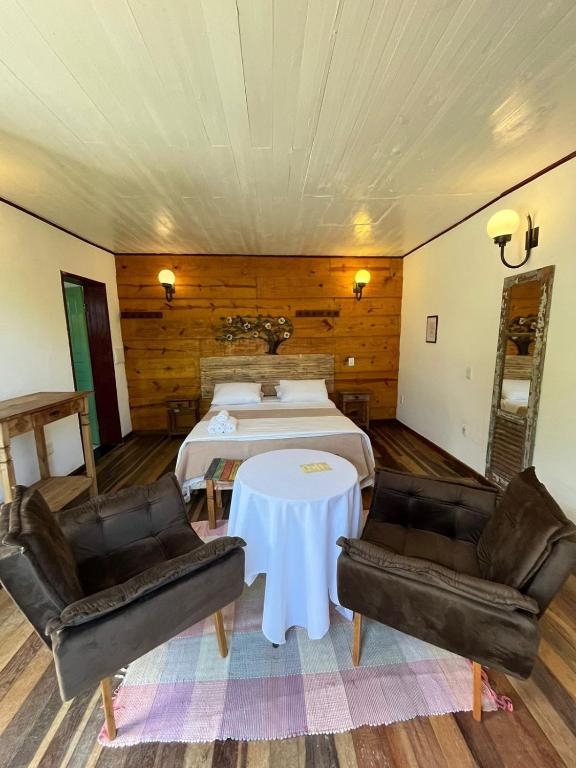 a bedroom with a bed and two chairs and a table at Pousada Sesmaria in Lavras Novas