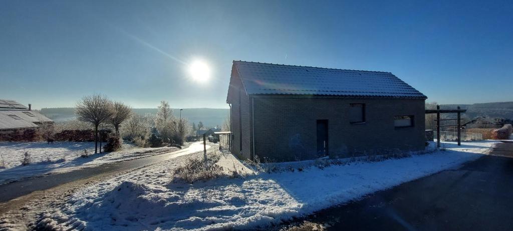 un granero en un camino cubierto de nieve con el sol detrás de él en Mont Là-Ô en Gedinne