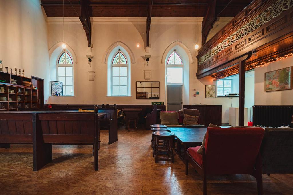 a large room with tables and chairs and windows at Kirkby Stephen Hostel in Kirkby Stephen