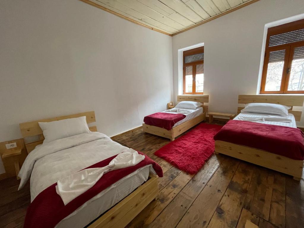 a bedroom with two beds and a red rug at Ardjon House in Berat