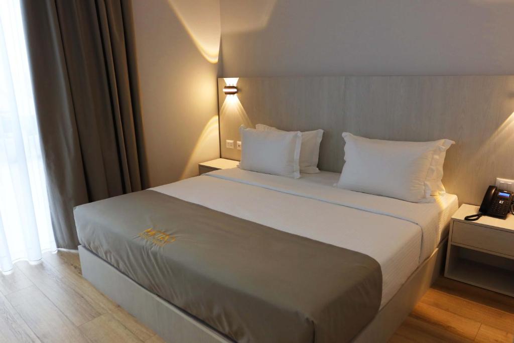 a bedroom with a large bed with white sheets and pillows at Metro Hotel Terminal in Tirana