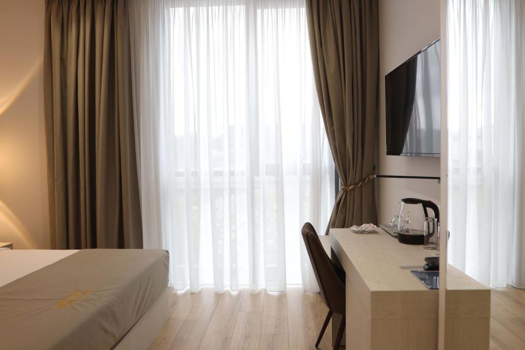 a hotel room with a bed and a desk with a television at Metro Hotel Terminal in Tirana