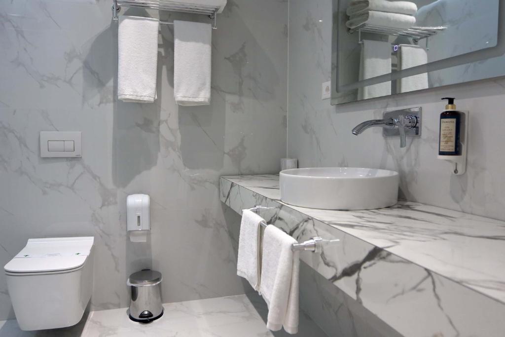 a white bathroom with a sink and a toilet at Metro Hotel Terminal in Tirana