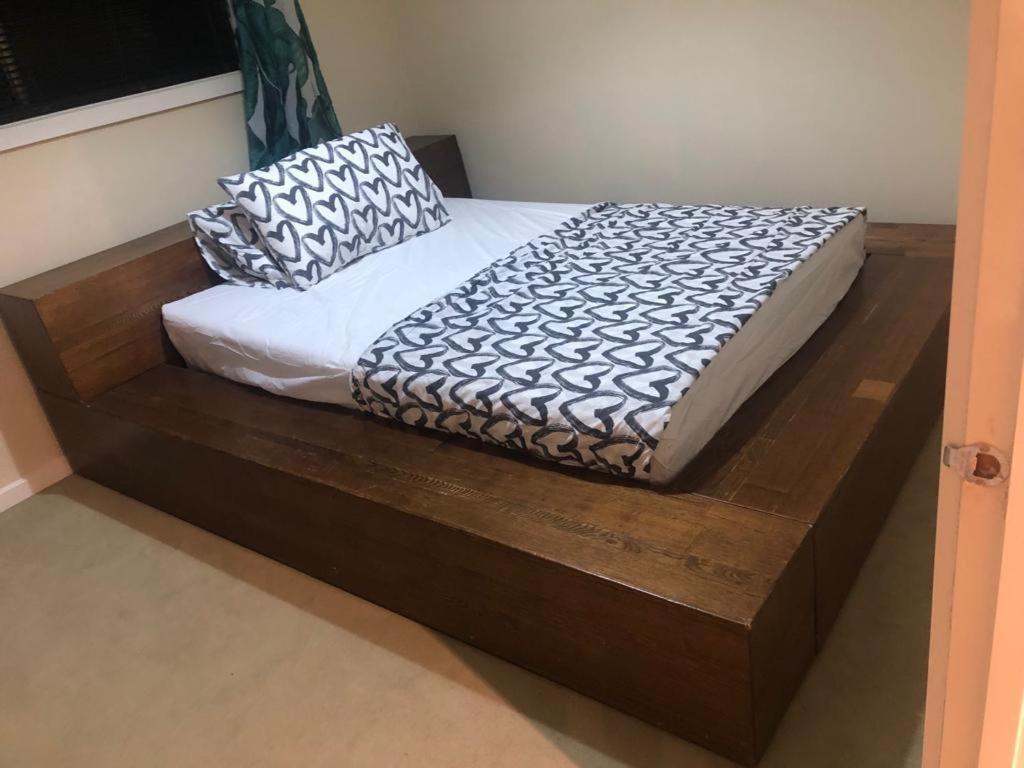 a wooden bed with two pillows on top of it at Prime home room no1 in Truganina