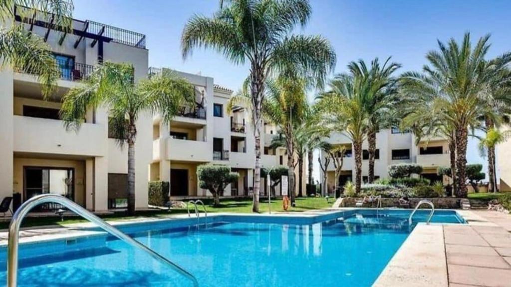 una piscina di fronte a un edificio con palme di Roda Golf Sunparadise a San Javier