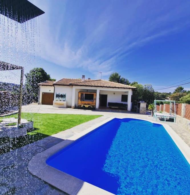 a blue swimming pool in front of a house at Casa Rural Zahoko in Guadalajara