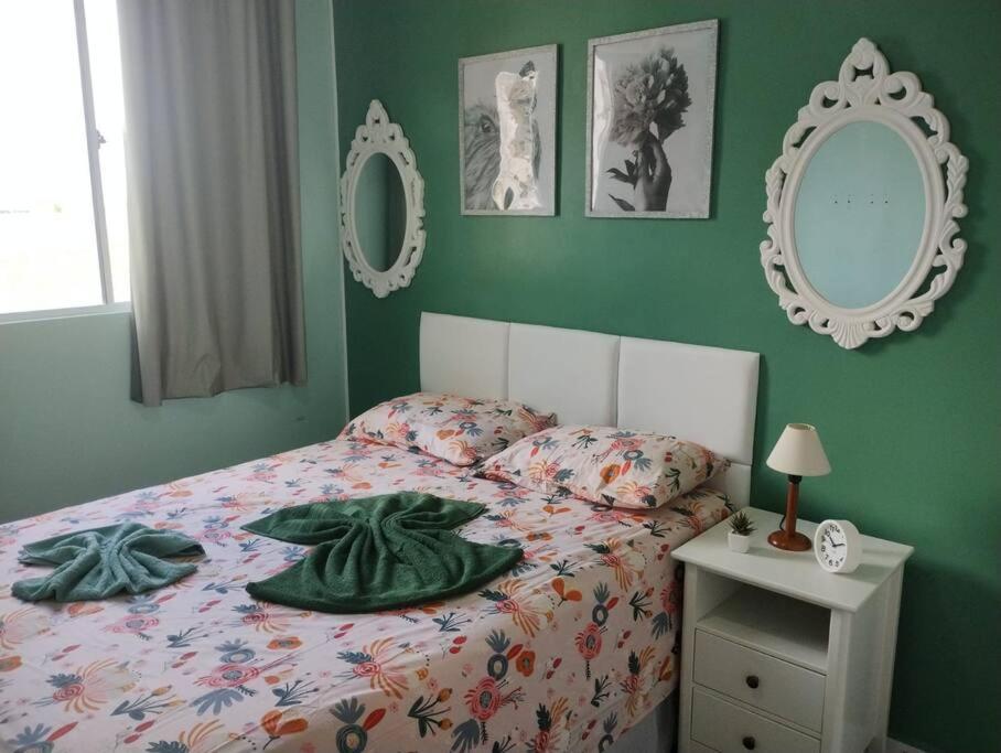 een bed in een slaapkamer met groene muren en spiegels bij Cantinho da Ju in Ipojuca