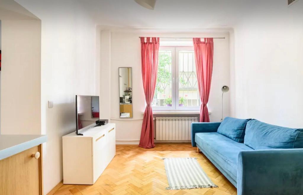 sala de estar con sofá azul y ventana en Cozy Apartment Praga, en Varsovia