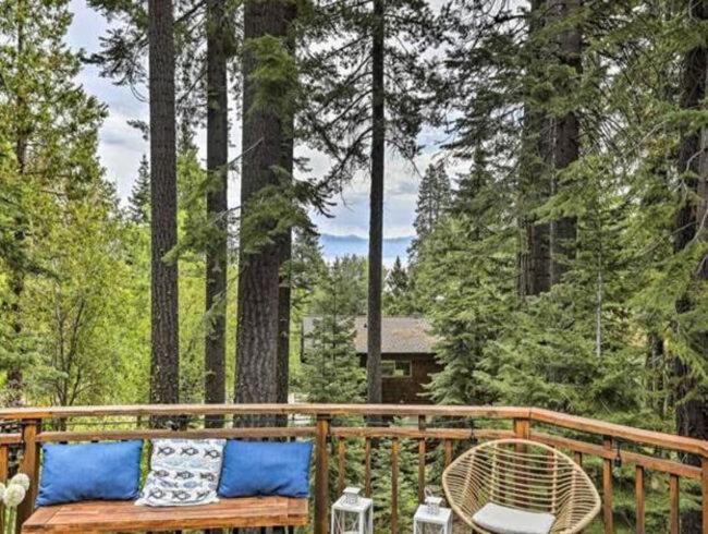 Homewood的住宿－Tahoe Oasis - West Shore Chalet with View & Hot Tub! home，甲板上配有带蓝色枕头的木制长凳