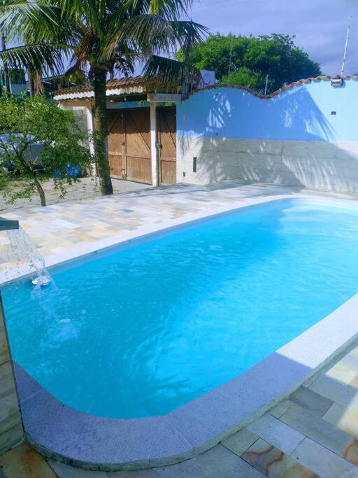 een groot blauw zwembad voor een huis bij Chácara com piscina em Itanhaém in Itanhaém