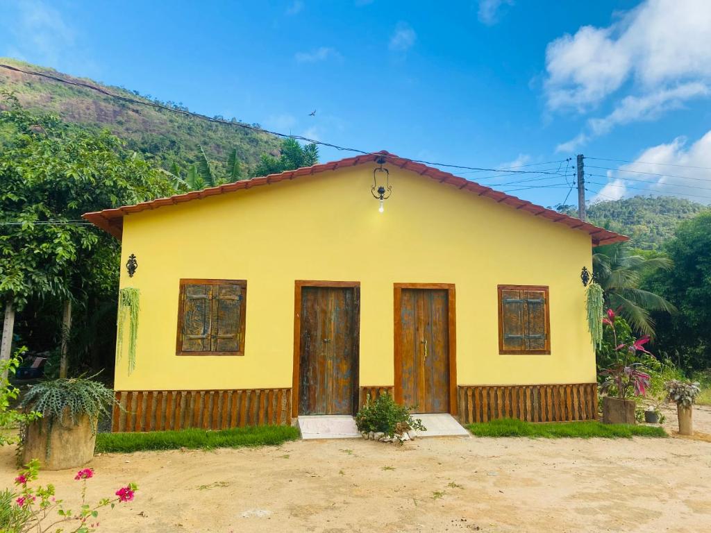 a yellow house with wooden doors and a mountain at Ferrari Casa Nostra in Santa Teresa