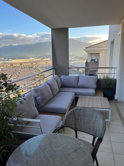 un balcon avec un canapé et des chaises sur un immeuble dans l'établissement Résidence calme proche des commerces et plages, à Sarrola-Carcopino