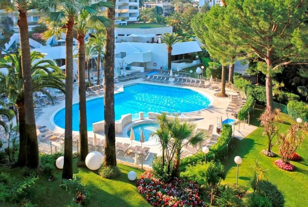 einen Blick über einen Pool mit Palmen in der Unterkunft Magnifique studio, piscine, Parking By Palmazur in Cannes