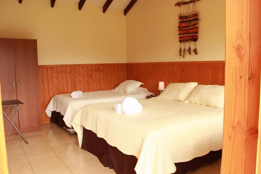 a hotel room with two beds with towels on them at Del Bosque Pucón - Hostal in Pucón