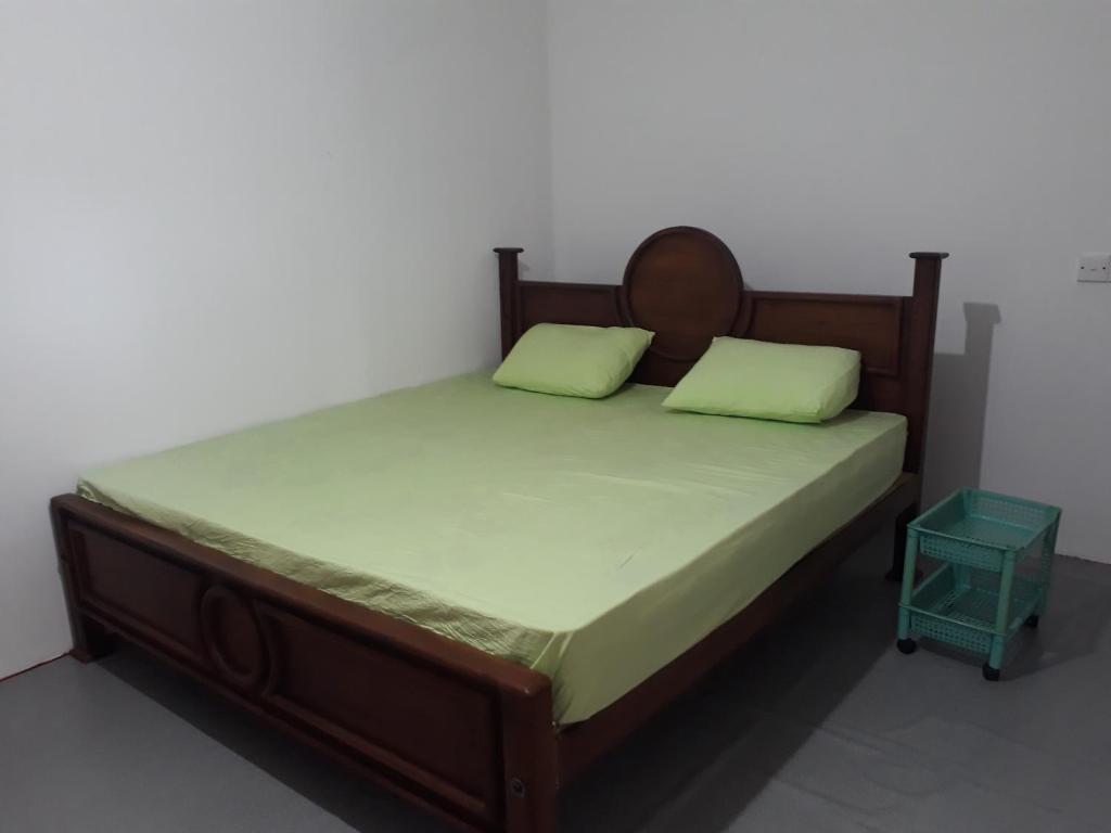 a bed with a wooden frame and two green pillows at G7 Villa in Weligama