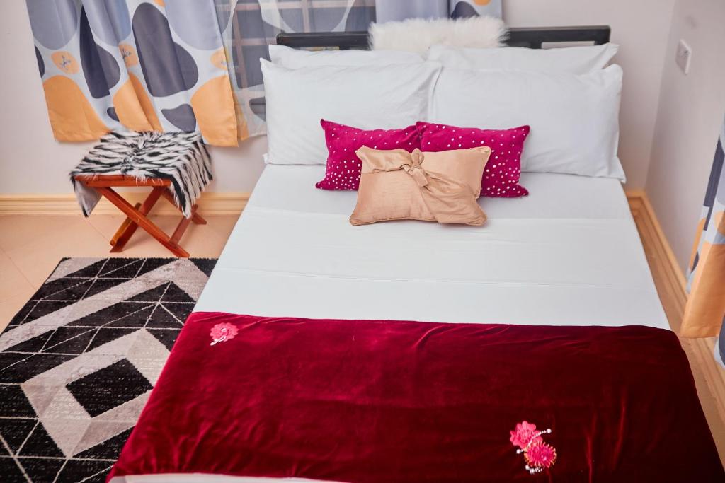 a bed with red and white pillows and a chair at Mama's Home Stay in Dodoma