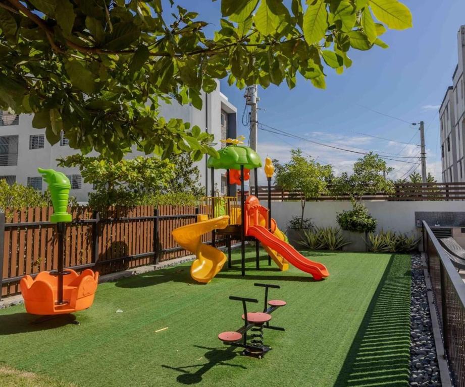 une aire de jeux avec toboggan sur une pelouse verdoyante dans l'établissement Tu penthouse en torre real Vl monumental, à Santiago de los Caballeros