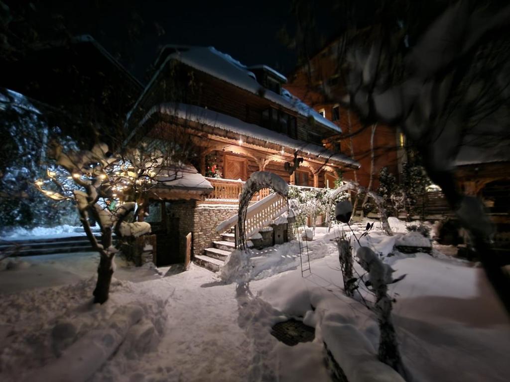 a snow covered yard with a building with lights at Casa IEUD in Sinaia