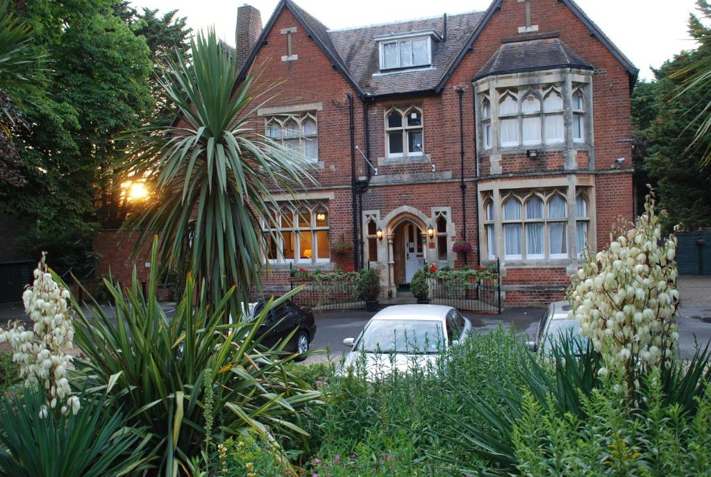 a brick house with cars parked in front of it at Beech House Hotel in Reading