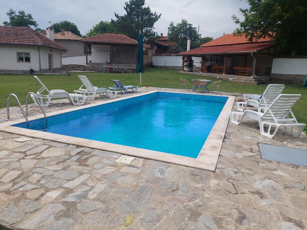 uma grande piscina com cadeiras e uma casa em Къщи за гости Мечта em Poroishte
