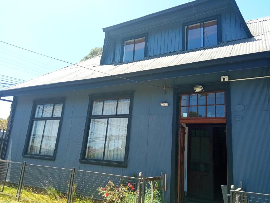 una casa azul con una puerta roja en HOSTAL FERNANDO en Valdivia