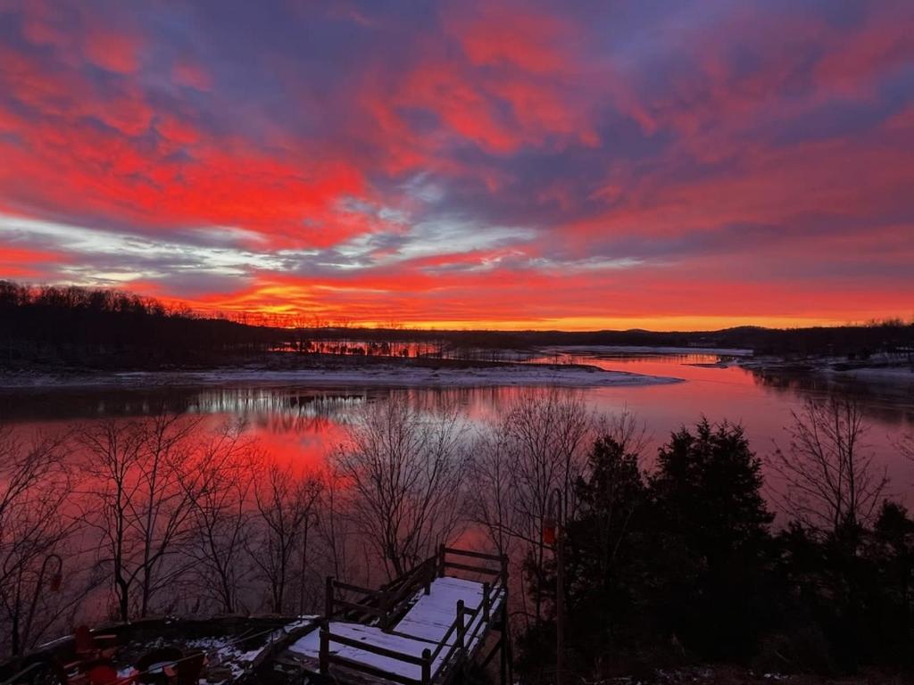 um pôr-do-sol sobre um lago com um banco na água em 530 Fentress Lookout Rd em Fentress McMahan