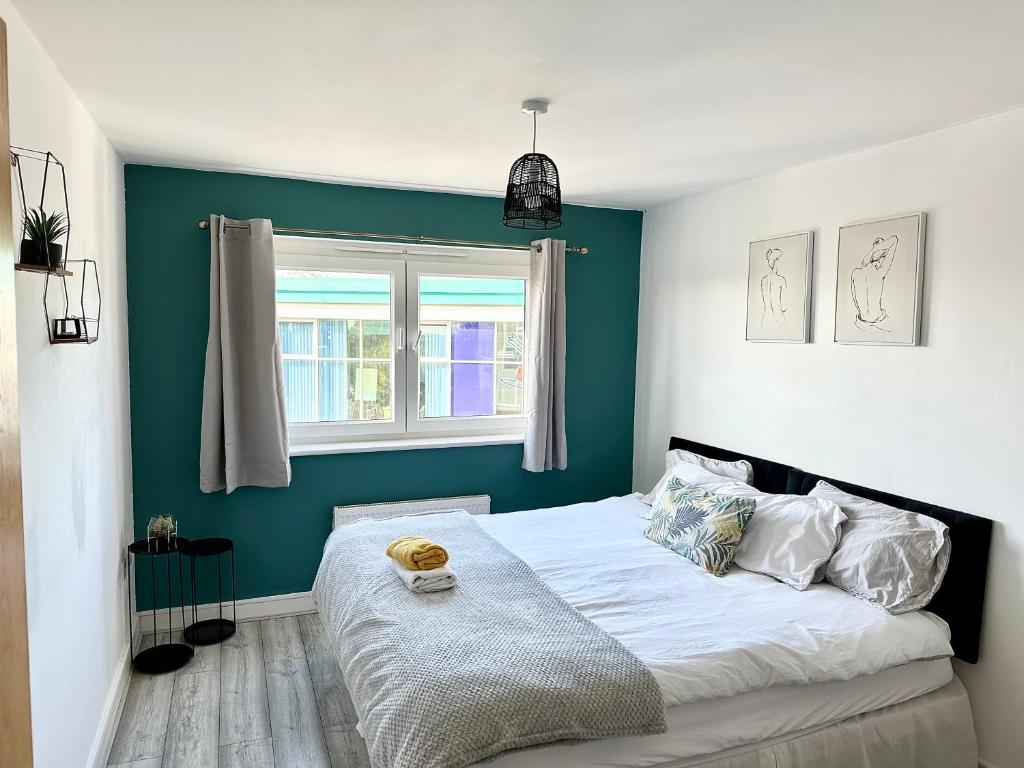 a bedroom with a bed with a blue wall at Cosy 2 Bed Apartment 5 min walk from London Tube Station in Barkingside