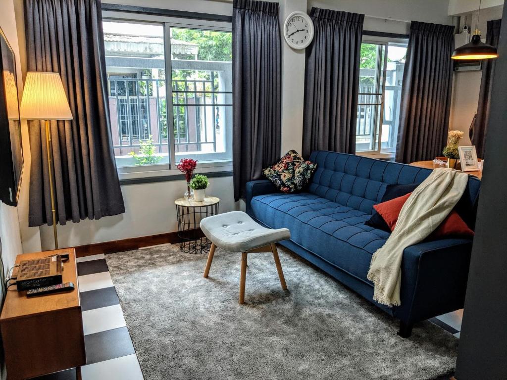 a living room with a blue couch and a table at Entire 2-storey house, 2 br, 2 toilet and shower, 2 car parks, only 400 m from MRT Huai Kwang in Ban Na Song