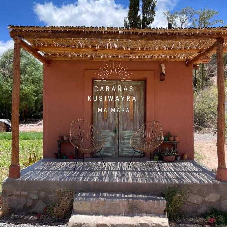 a building with two chairs in front of a door at KUSY WAYRA in Maimará