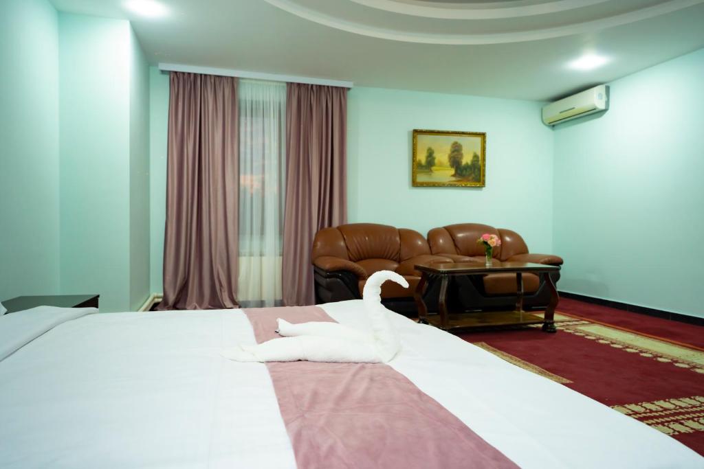 Continental New Hotel في يريفان: جلسة بجعة على سرير في غرفة فندق